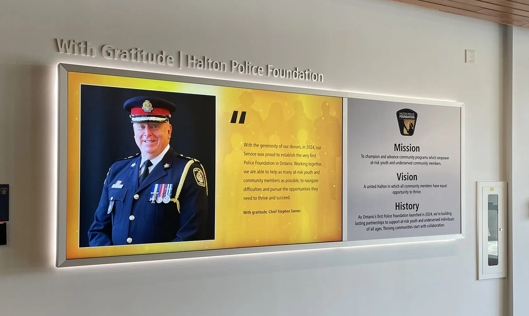 The installed Halton Police Foundation Designer Series wall, dimensional lettering reading “With Gratitude | Halton Police Foundation” above a landscape digital display and a Mission, Vision and History panel
