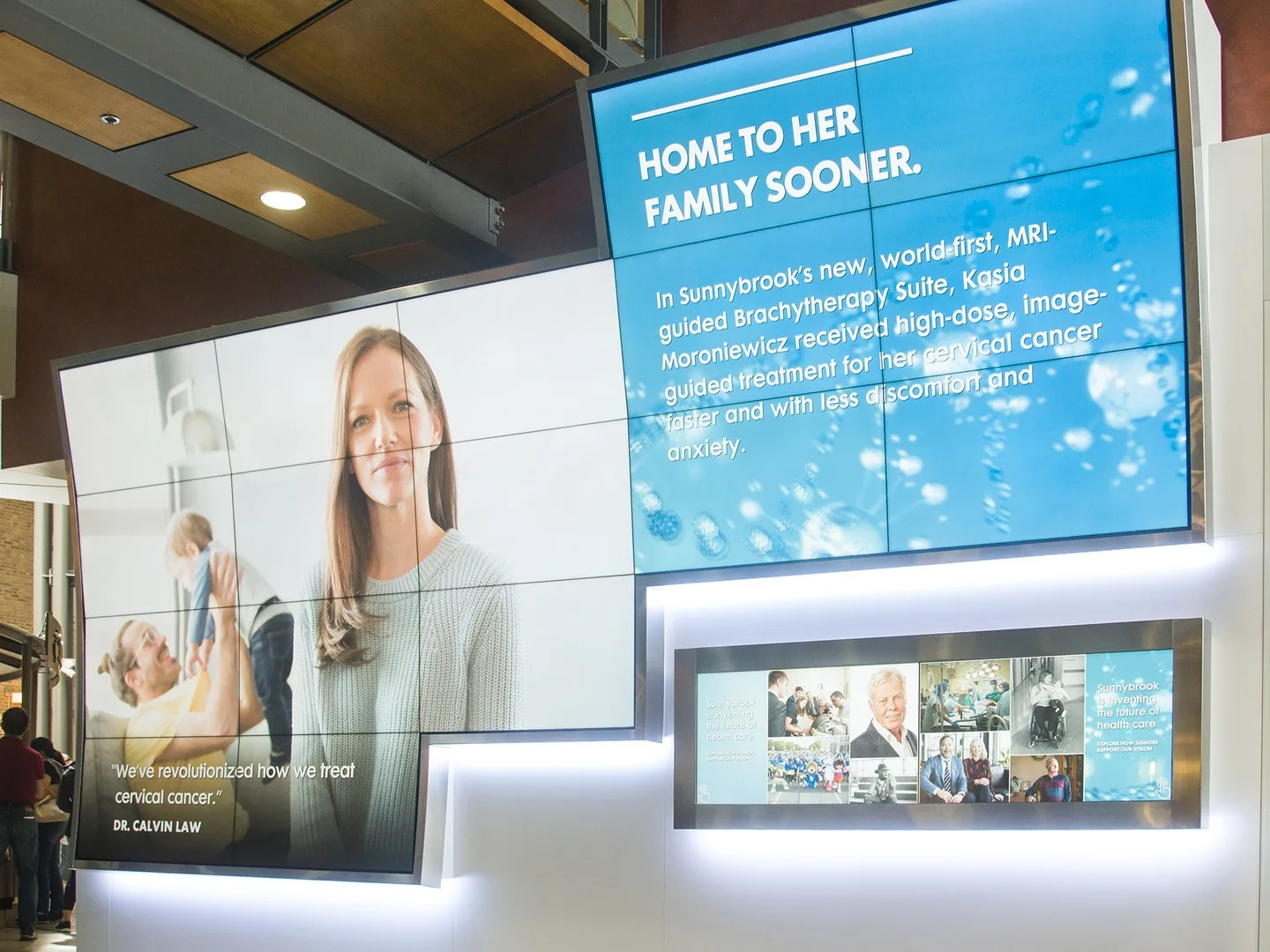 The full Sunnybrook donor fixture, the headline screen reading “Home to her family sooner” above the lower display strip and illuminated base